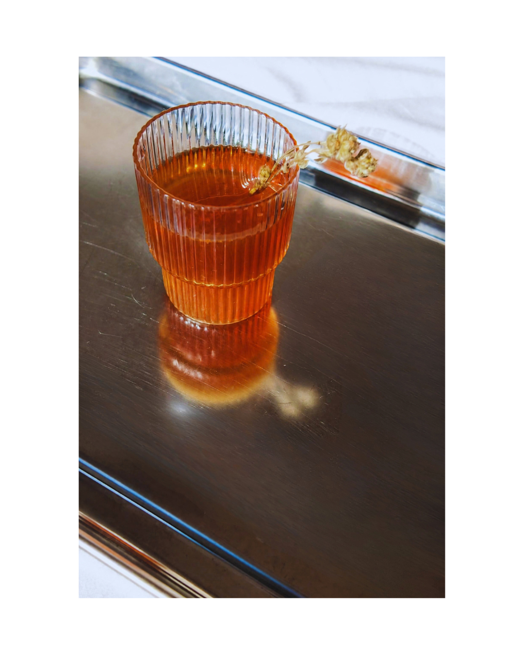 Verre de Grand Sirac avec un brin de génépi sur un plateau métallique